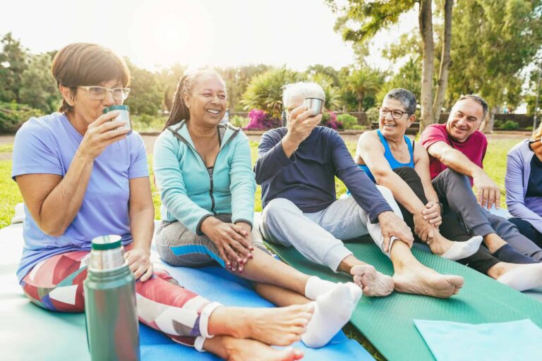 Senior people chatting and drinking hot green tea after yoga class